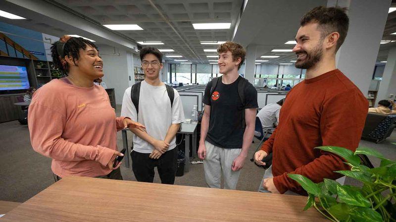 four students talking in the library